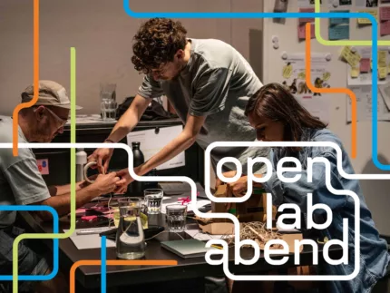 Drei Leute sitzen an einem Tisch und basteln. Unten rechts das Logo "open lab abend".