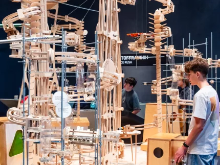 Ein Teenager steht vor einer Holzinstallation