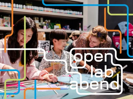 Zwei Erwachsene und ein Kind basteln am Tisch.